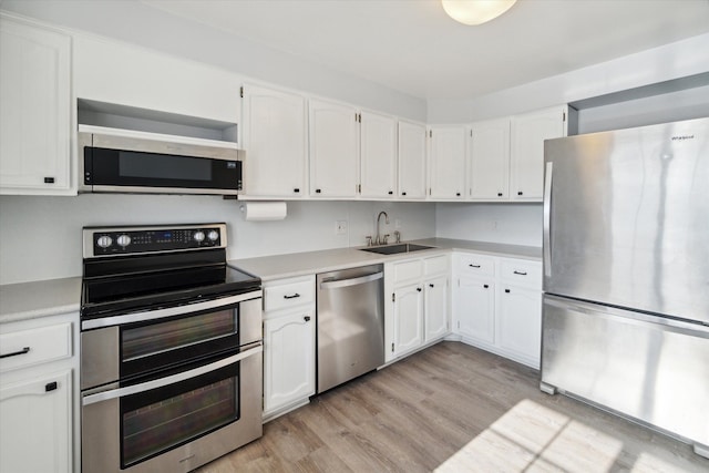 kitchen featuring stainless steel appliances, white cabinetry, and a sink