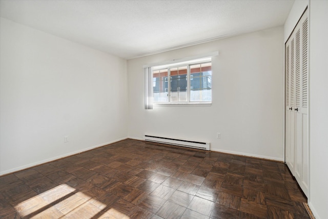 unfurnished bedroom with baseboard heating, a closet, and baseboards