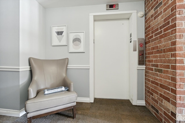 living area featuring carpet floors, elevator, baseboards, and brick wall