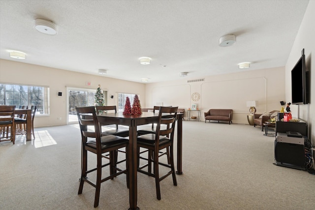 carpeted dining room with a textured ceiling