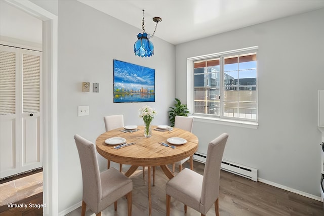 dining space with a baseboard radiator, wood finished floors, and baseboards