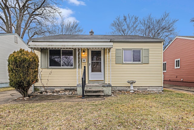 bungalow-style house featuring entry steps, a chimney, and a front yard