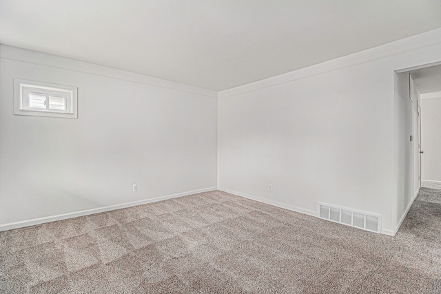 spare room featuring carpet floors, ornamental molding, visible vents, and baseboards