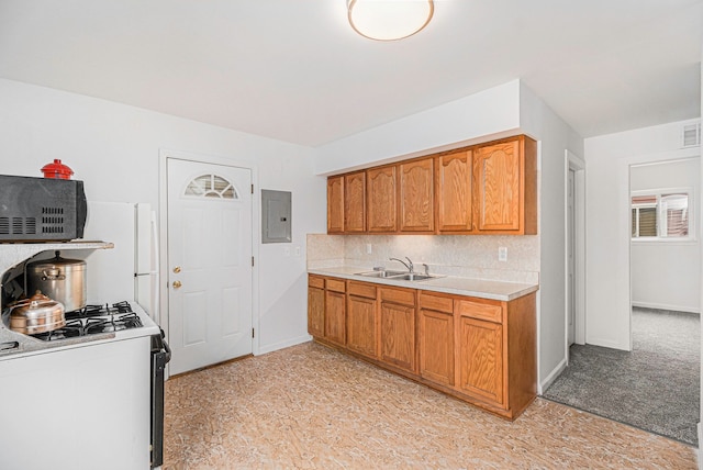 kitchen with a sink, light countertops, electric panel, decorative backsplash, and gas range oven