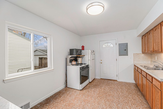 kitchen with white appliances, a sink, visible vents, light countertops, and electric panel