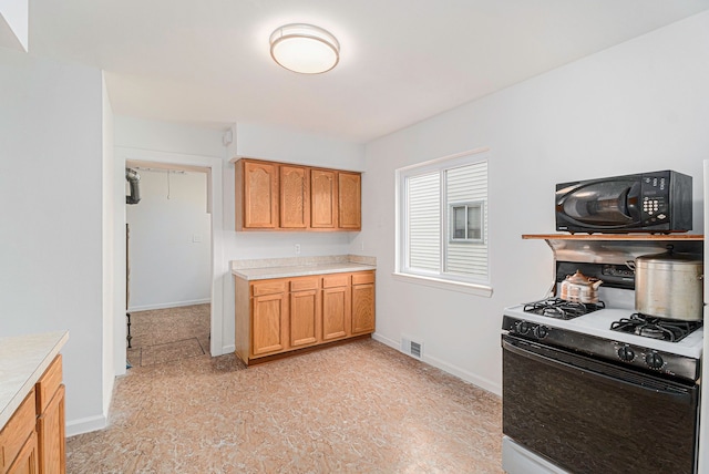 kitchen with visible vents, baseboards, range with gas cooktop, light countertops, and black microwave