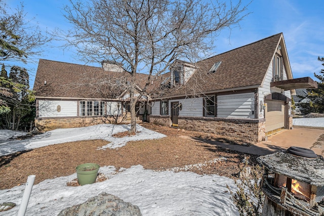 view of front facade featuring brick siding, a chimney, and a shingled roof