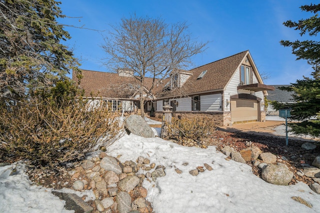 back of house with brick siding and roof with shingles