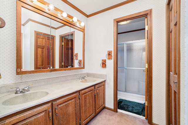 bathroom with a sink, ornamental molding, a shower stall, and wallpapered walls
