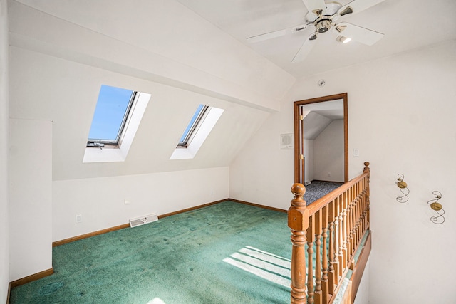additional living space with visible vents, lofted ceiling with skylight, a ceiling fan, carpet, and baseboards