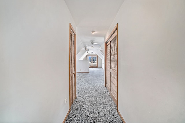 hallway featuring carpet flooring and vaulted ceiling