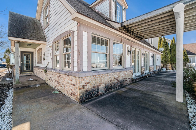 view of home's exterior with brick siding and roof with shingles