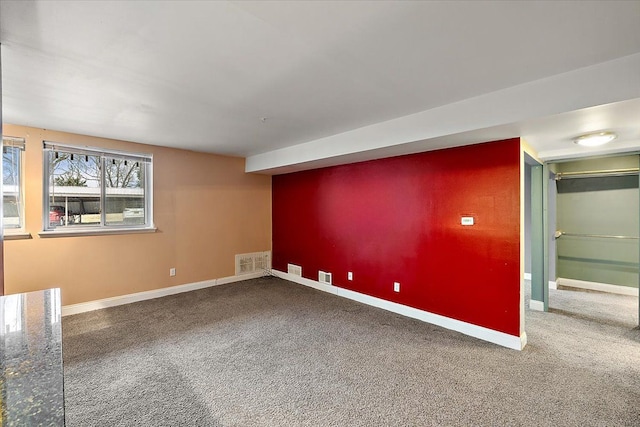 unfurnished room featuring carpet flooring, visible vents, and baseboards