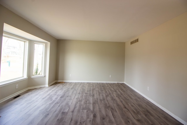 spare room featuring baseboards, visible vents, and dark wood-style flooring