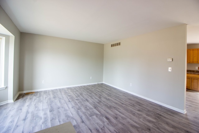 unfurnished room featuring visible vents, baseboards, and wood finished floors