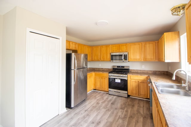 kitchen featuring appliances with stainless steel finishes, light wood-style floors, light countertops, and a sink