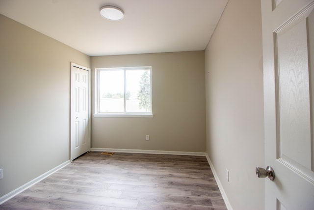 unfurnished bedroom featuring light wood-style flooring, baseboards, and a closet