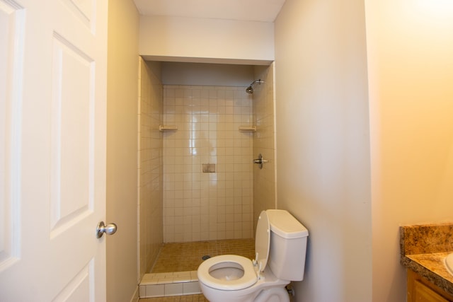 bathroom with tiled shower, vanity, and toilet