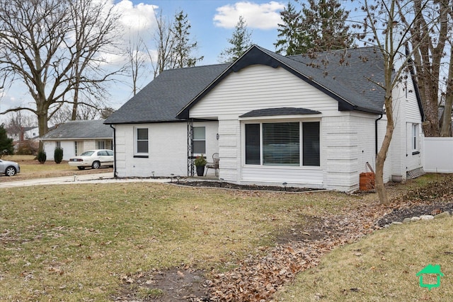 view of front facade with roof with shingles, brick siding, and a front lawn