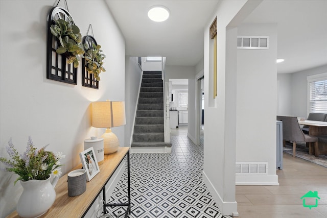 hall with baseboards, stairs, and visible vents