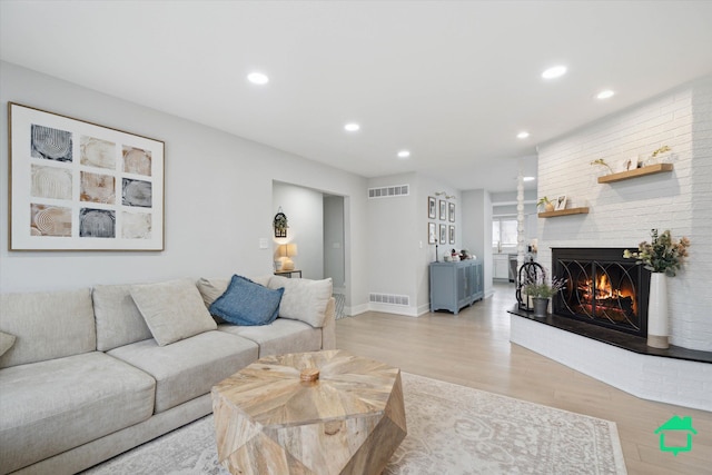 living area with recessed lighting, visible vents, a fireplace, and light wood-style flooring