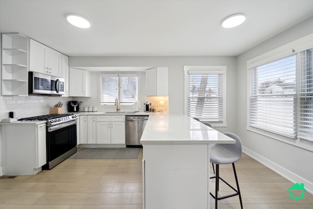 kitchen with stainless steel appliances, a breakfast bar area, a peninsula, and light wood-type flooring