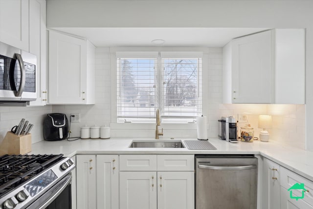 kitchen with white cabinets, tasteful backsplash, stainless steel appliances, and a sink