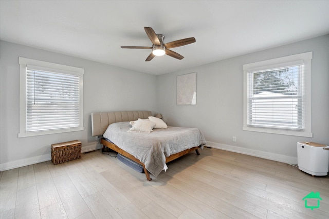 bedroom with multiple windows, wood finished floors, and baseboards