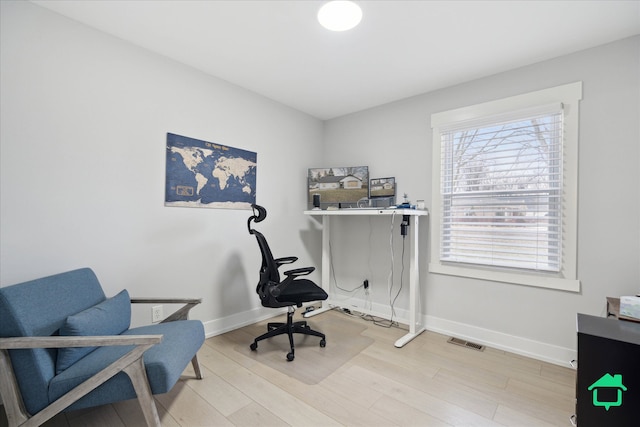 home office with light wood-style flooring, visible vents, and baseboards