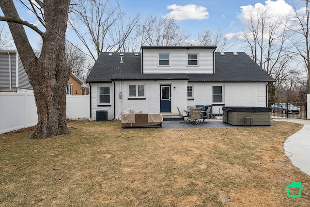 back of house with a hot tub, a patio, fence, a yard, and brick siding