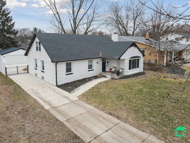 ranch-style house with a shingled roof, an outdoor structure, a chimney, and a front lawn