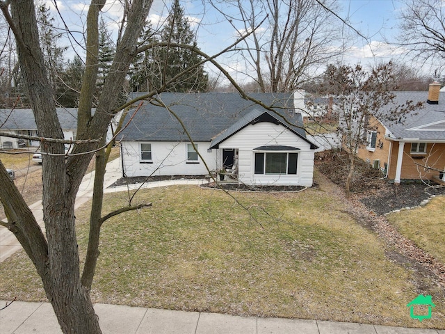 view of front of house with roof with shingles and a front lawn