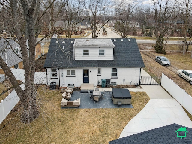 rear view of property featuring a fenced backyard, a gate, roof with shingles, and a yard