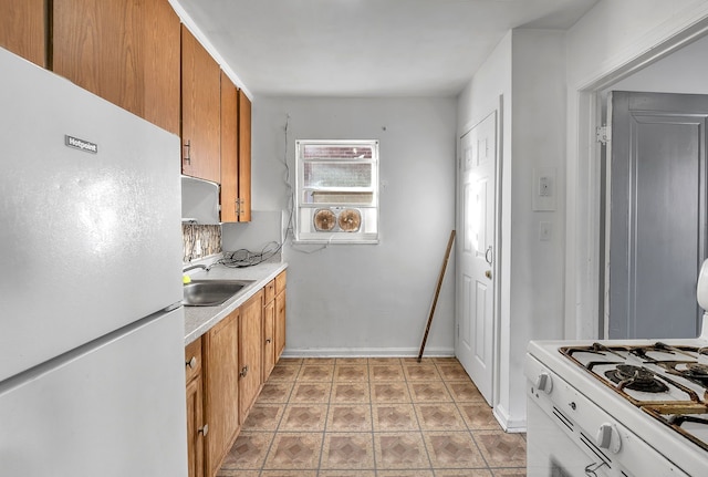 kitchen featuring white appliances, baseboards, brown cabinetry, light countertops, and a sink