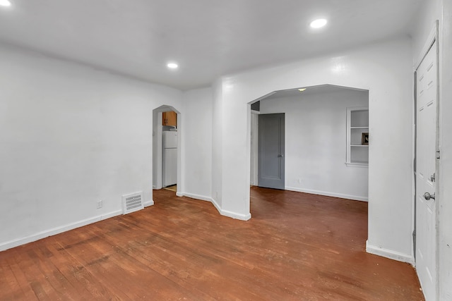 unfurnished room with arched walkways, recessed lighting, visible vents, wood finished floors, and baseboards