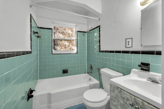 bathroom featuring toilet, a wainscoted wall, shower / bath combination, vanity, and tile walls