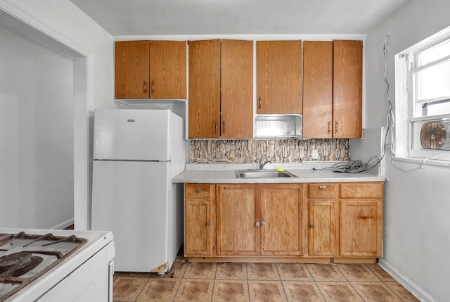 kitchen with light countertops, white appliances, brown cabinetry, and a sink