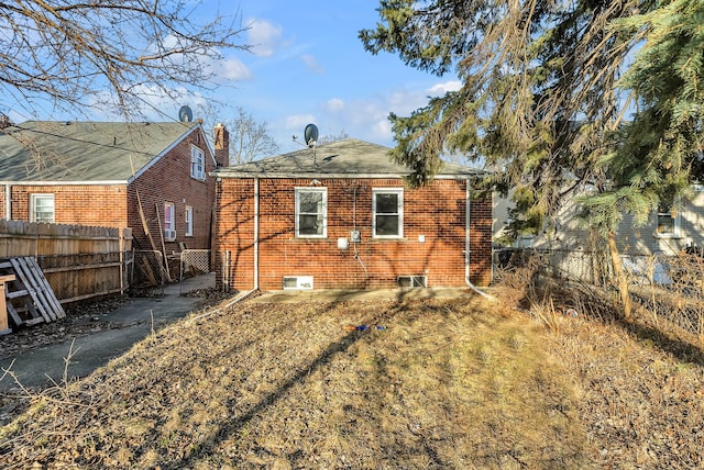 back of house with brick siding and fence