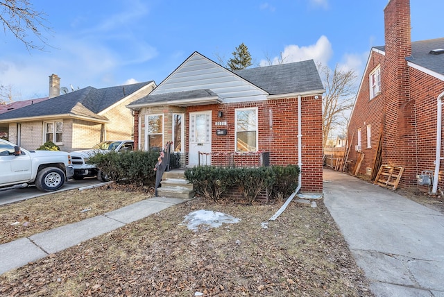 bungalow-style house with roof with shingles and brick siding