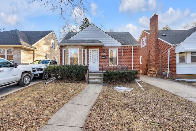 bungalow with a shingled roof and brick siding