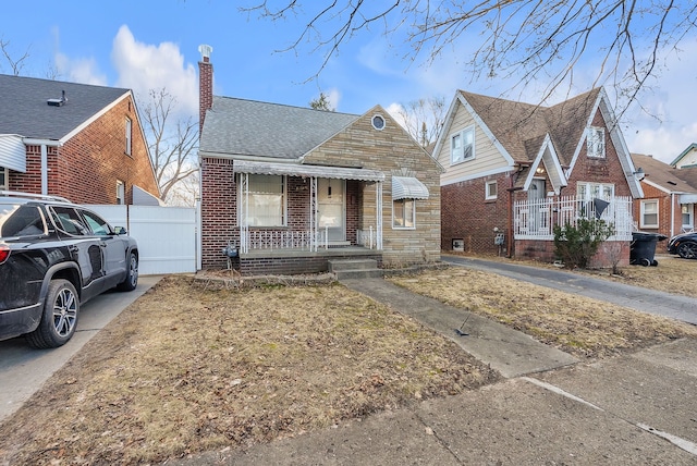 view of front of home featuring roof with shingles, a chimney, fence, and brick siding