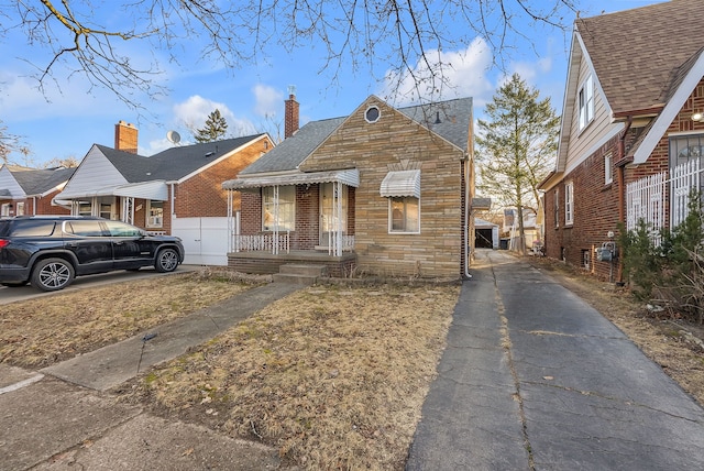 view of front of property with a shingled roof, stone siding, and driveway