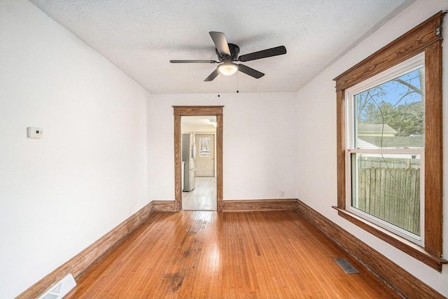 spare room featuring wood-type flooring, a textured ceiling, visible vents, and baseboards