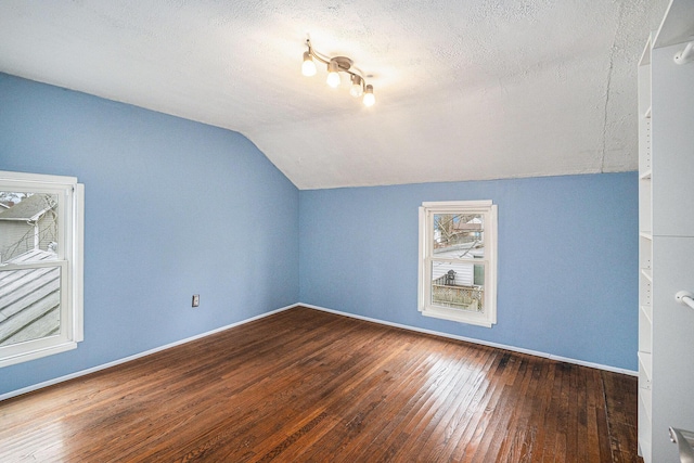 bonus room featuring lofted ceiling, wood-type flooring, baseboards, and a textured ceiling