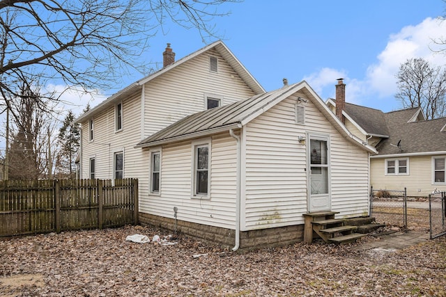 back of property featuring entry steps, a chimney, and fence