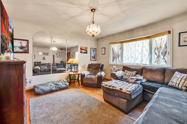 living area with arched walkways, wood finished floors, and an inviting chandelier