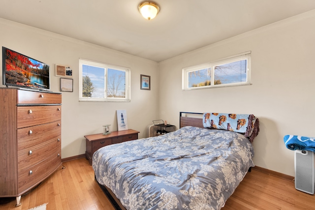 bedroom featuring baseboards, ornamental molding, and light wood-style floors