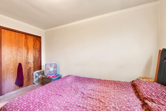 carpeted bedroom with ornamental molding and a closet