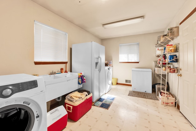 clothes washing area featuring laundry area, a sink, visible vents, independent washer and dryer, and tile patterned floors