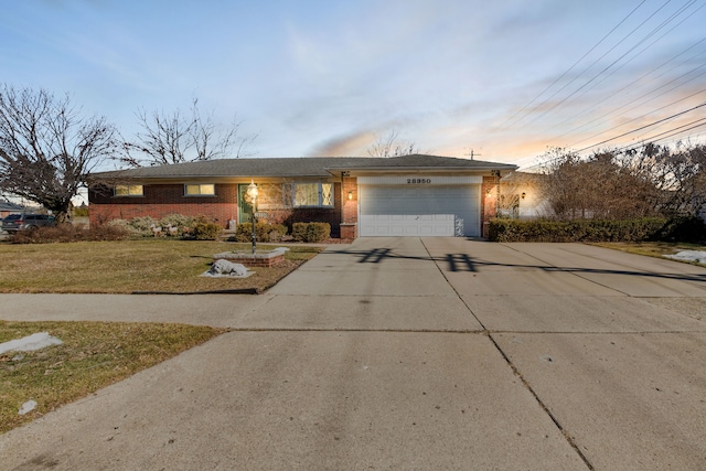 view of front of property featuring driveway, a garage, a front lawn, and brick siding